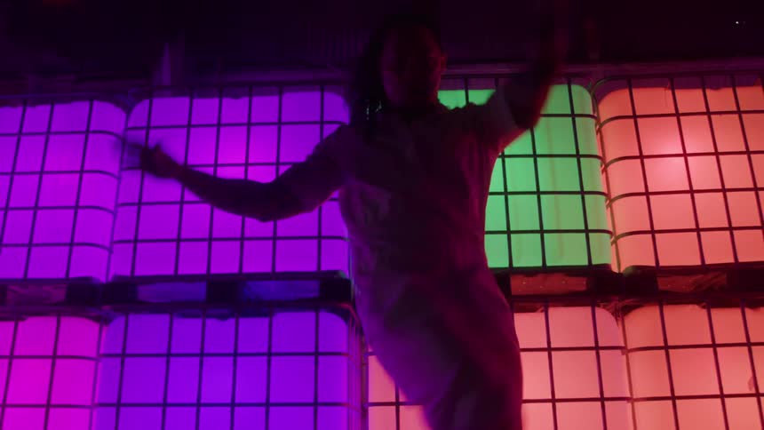 A young man dancing in a room illuminated with different colours
