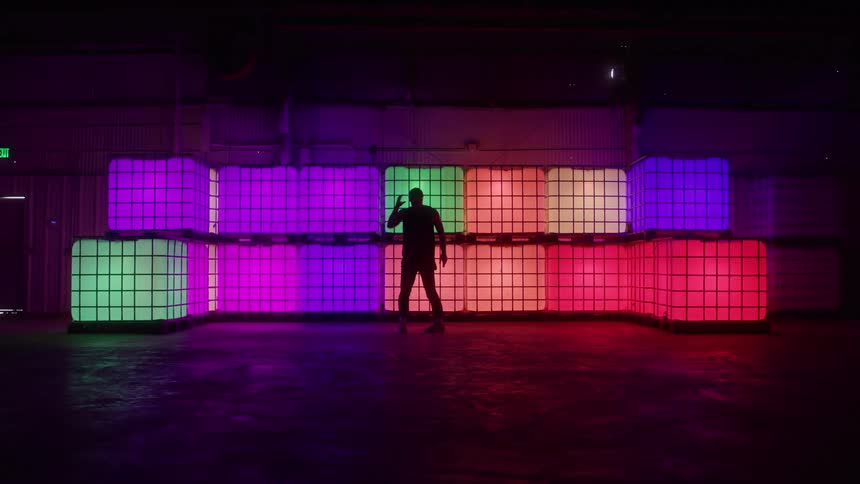 A male dancer performs popping and locking moves in front of illuminated cubes