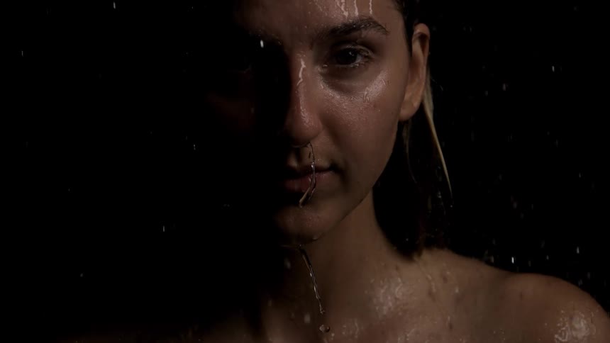 Woman with water streaming down her face in a dimly lit setting