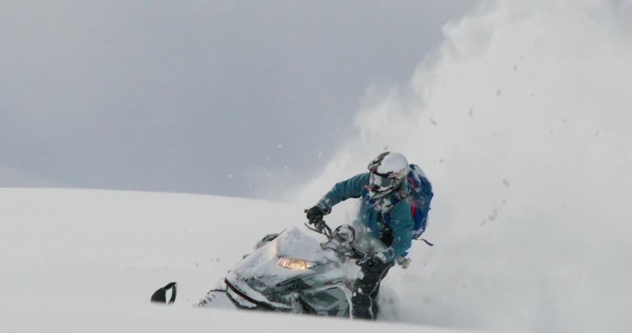 Person rides a snowmobile kicking up a large cloud of white powder