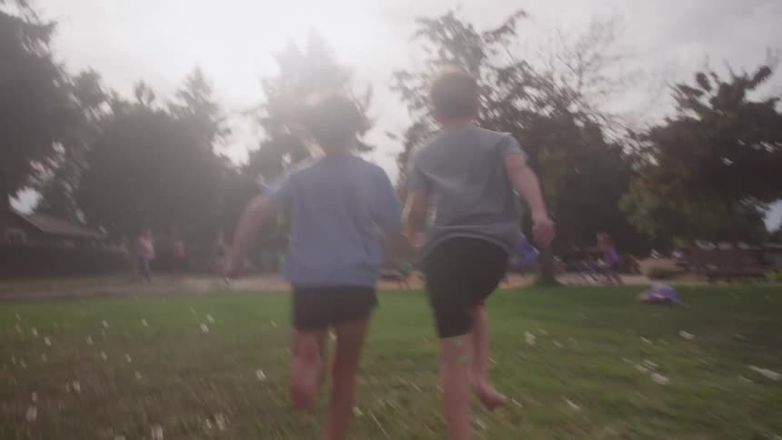 Two children run toward a park on a sunny day