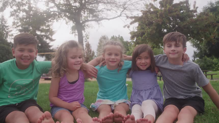 The children sit together on the grass in the park