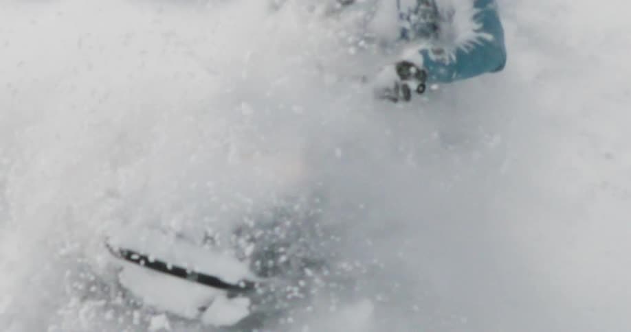 The man turns the snowmobile causing a wave of snow to fly