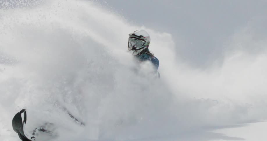 The person shoots snow everywhere while riding the snowmobile