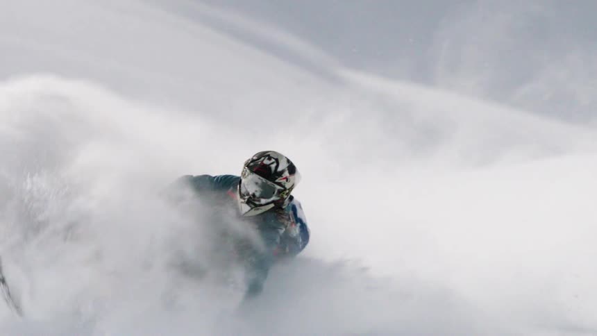 The man moves up and down as he rides on the snowmobile through the heavy snow