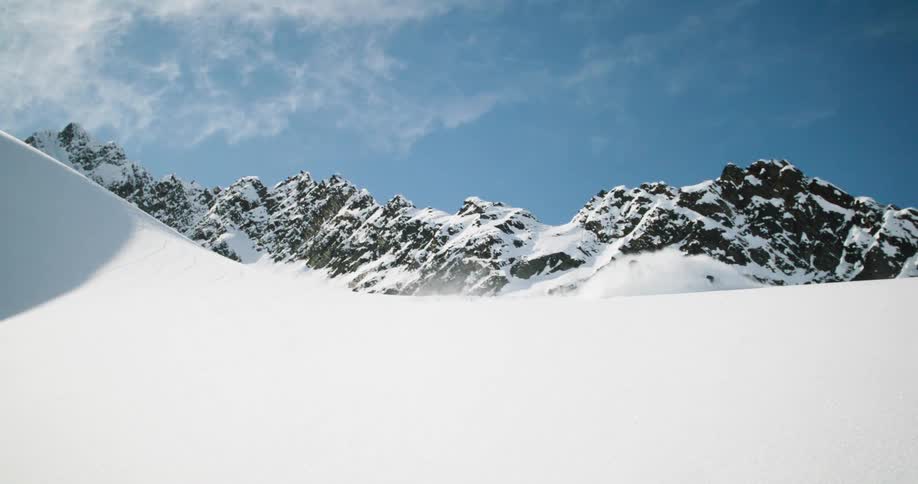 Person rides a snowmobile at high speed down a snowcovered slope
