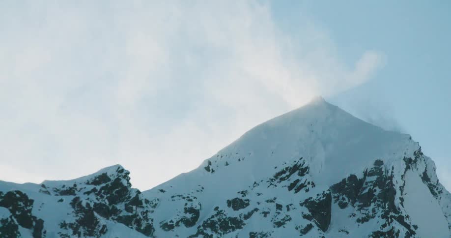 Snowcovered mountain peak with winds lifting icy dust