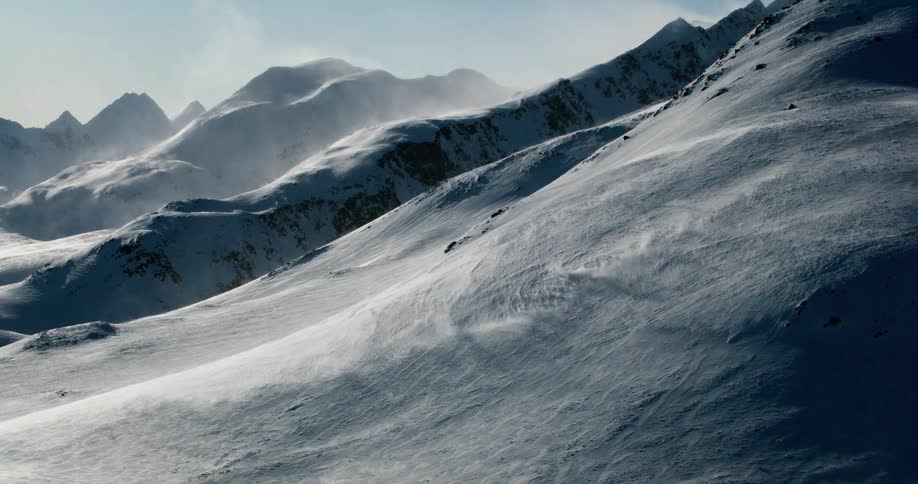 Snowcovered mountain range with soft light illuminating the slopes