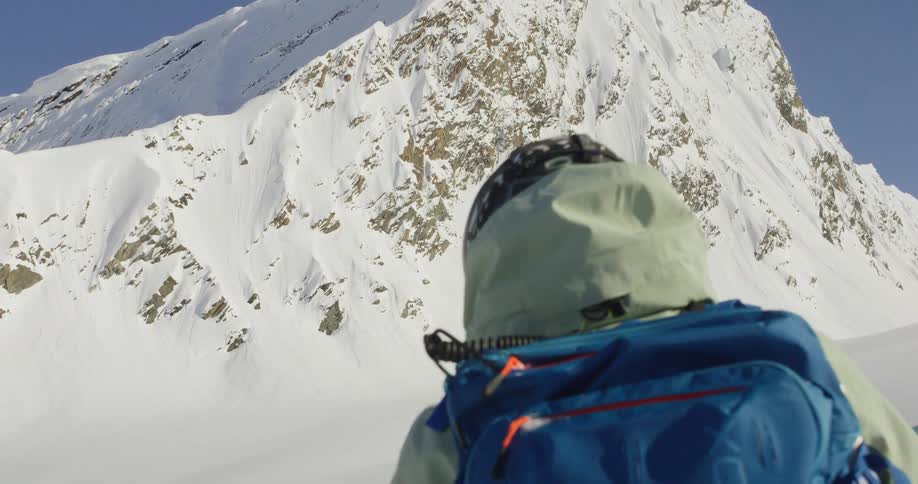 The man is examining a snowboard on the mountain