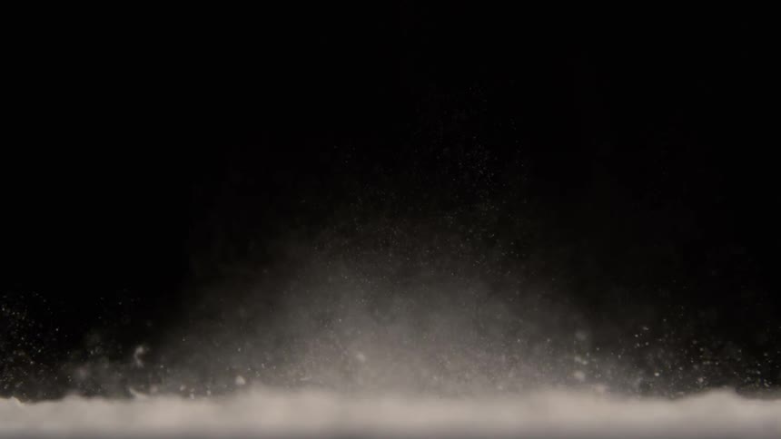 Several dust particles are rising upwards on a completely black background