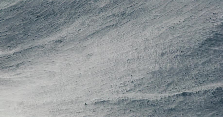 The video clip is an abstract shot of a snowcovered surface with an overcast or diffused light the textured snow fills the entire frame and appears to be heavily windscoured or powdered