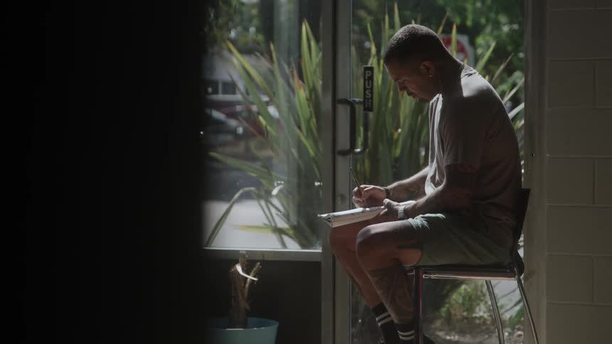 Man sitting near the door writing in a notebook