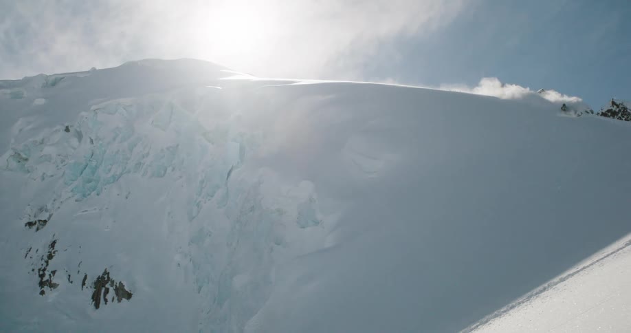 Person rides a snowmobile at high speed down a steep slope