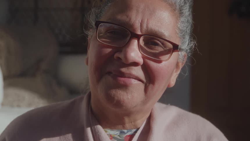 Elderly woman smiles softly under sunlight