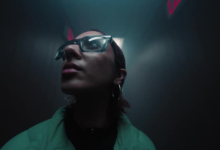 Close up portrait of a young woman walking through a lit corridor in a building at night