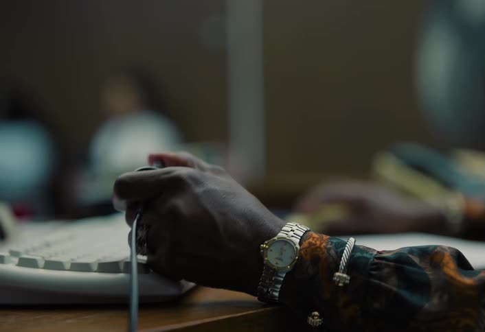 Hand holds and presses a button connected to a keyboard on the desk