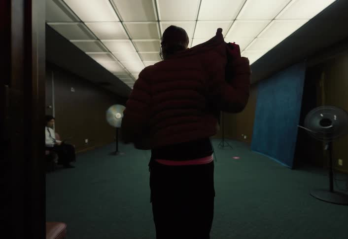 Woman walks down a bright hallway taking off her jacket