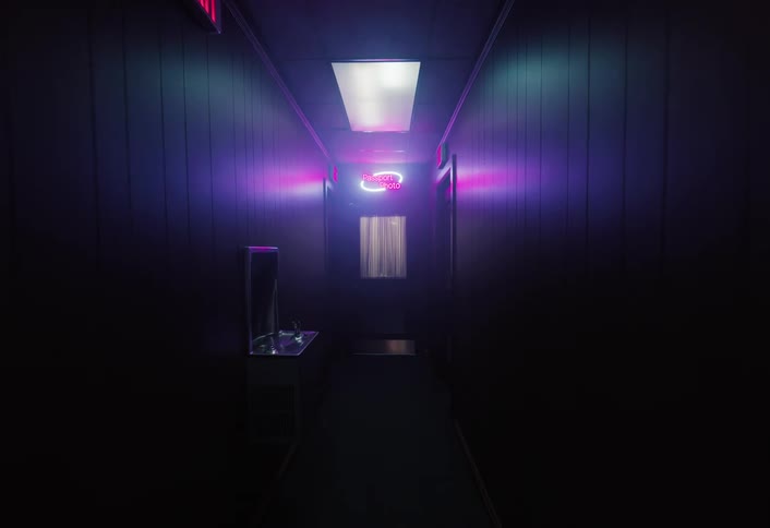 Curtain lit by a pink and blue neon sign reading passport photo