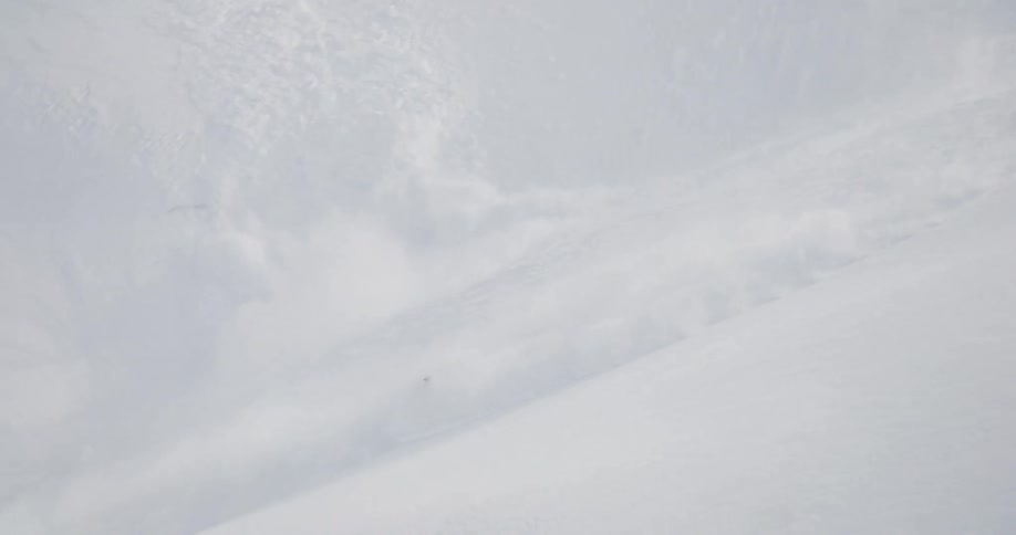 A snowmobiler triggers an avalanche while riding down a slope