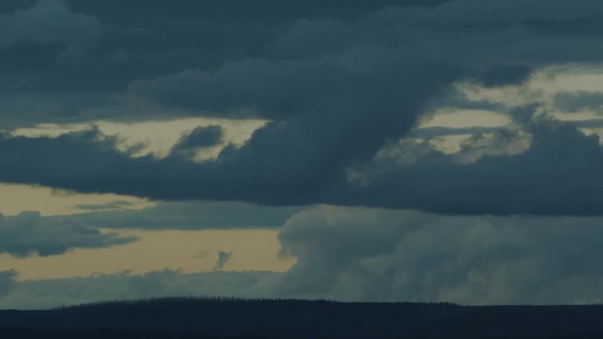 Heavy clouds are over the forest at sunrise