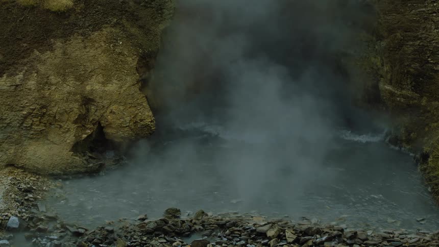 Steam rises from hot springs near a cliff