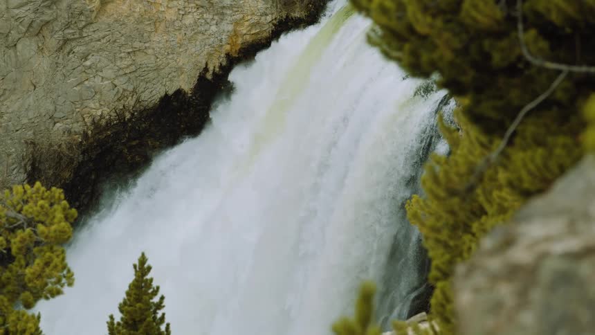 Waterfall cascades powerfully between rocks and pine trees