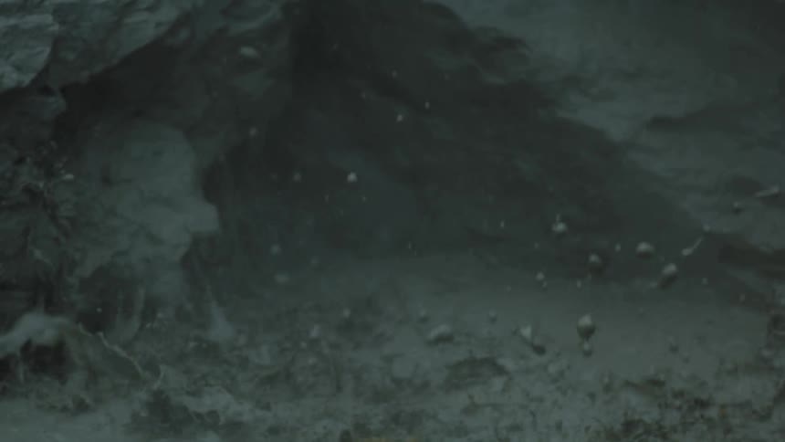 Explosion of mud and debris against a rocky wall