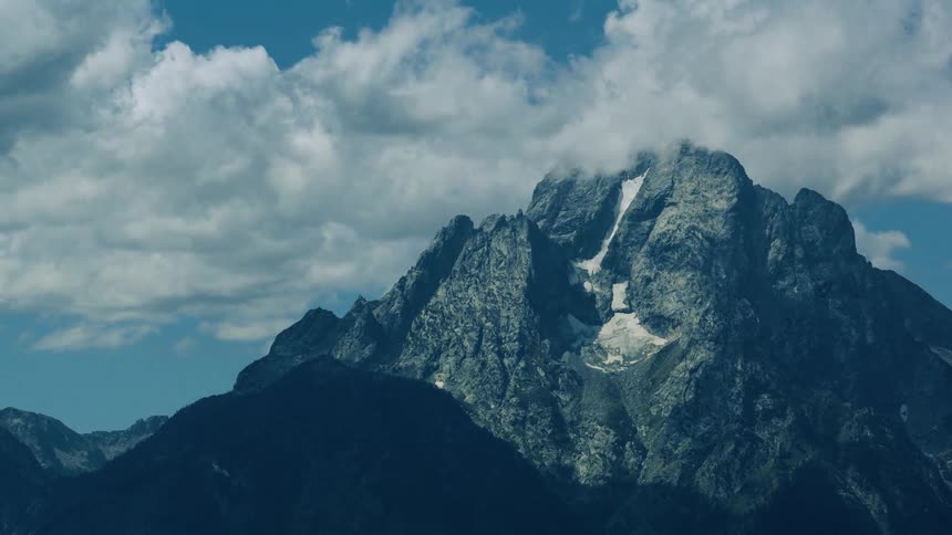 Rocky mountain with patches of snow under a partly cloudy sky