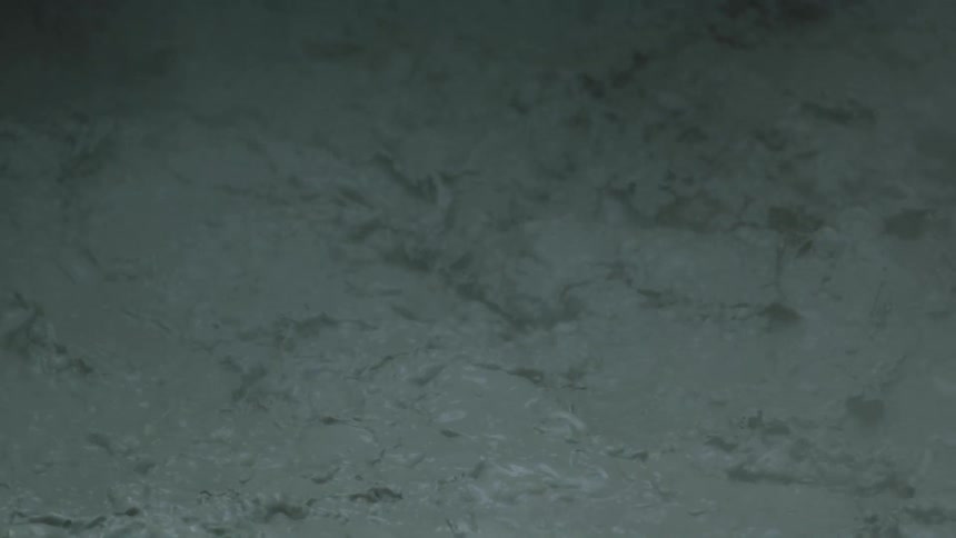 A close view of murky grey water churns and ripples as suspended silt gives the surface a smoky look
