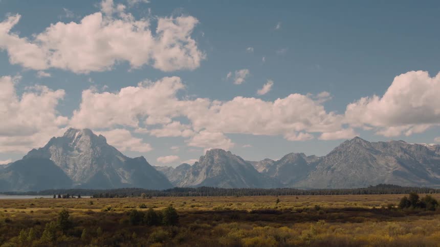 Mountain range cutting across the horizon under a blue sky with scattered clouds