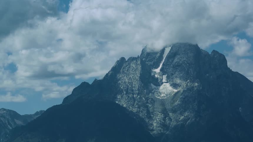 Snowcapped mountain peak rises amid dense clouds