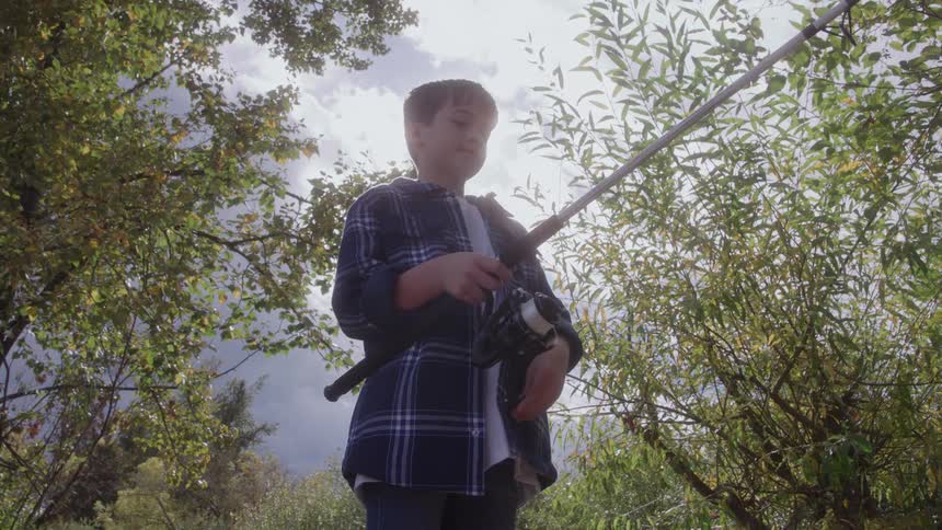 A boy reels in a fishing line