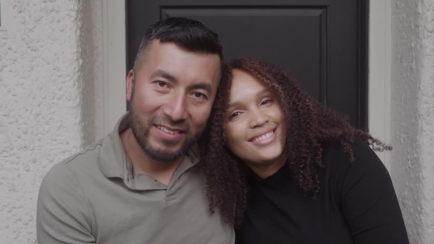 A man and a woman looking forward smiling and the woman after her head on the mans shoulder