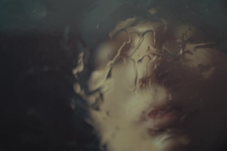 Translucent textured pane blurs the face of a person looking around