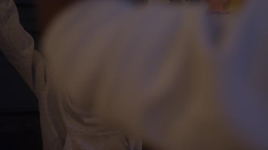 The video is a mediumcloseup shot of a young boys face against a dark background he is wearing glasses and a lightcolored hooded sweatshirt looking forward with a serious contemplative expression