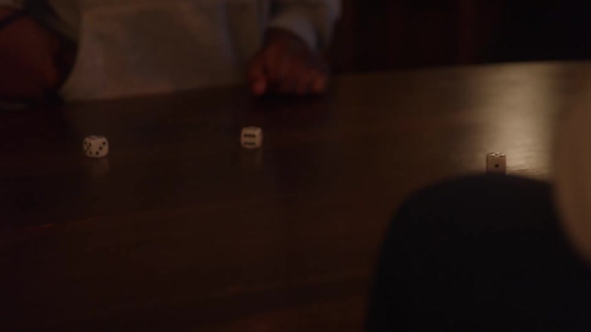 White dice are rolled across a wooden table during a game