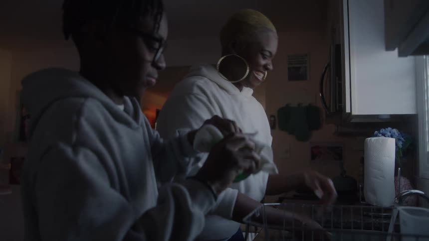 Mother and child playfully do the dishes together at home