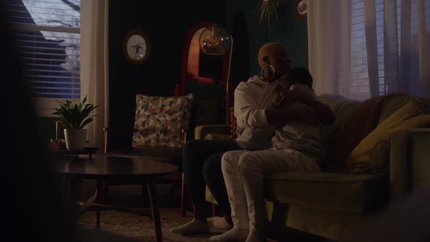 Mother and son embrace on the couch as the evening light fills the room