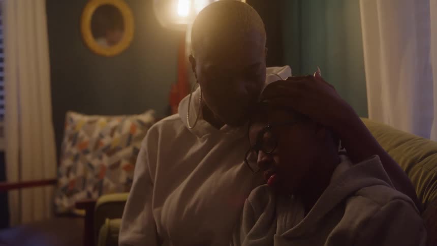 Mother comforts her son with a gentle gesture under the rooms soft light