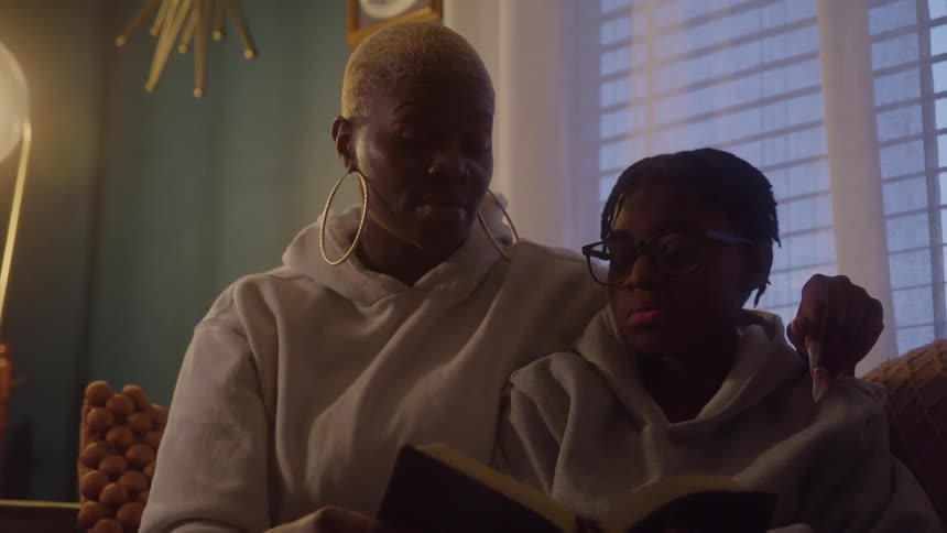 Mother and son read together on the couch focused under soft light