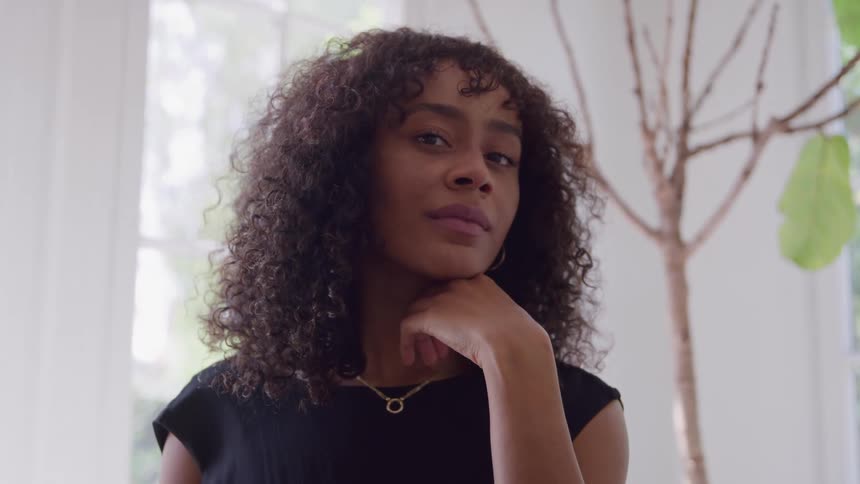 Woman with curly hair looks into the camera in a softly lit room