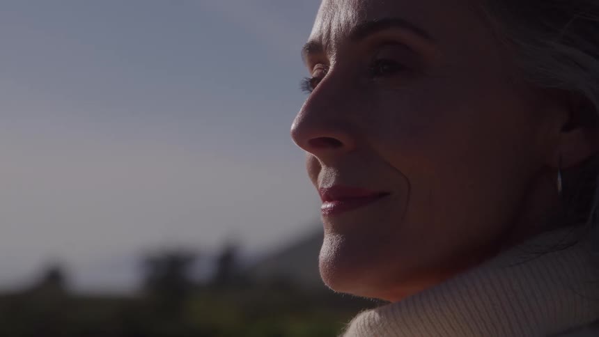 Woman gazes at the horizon with a serene expression under sunlight