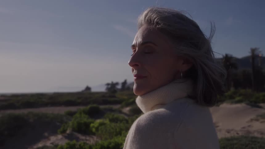 Grayhaired woman smiles gently while enjoying the coastal scenery