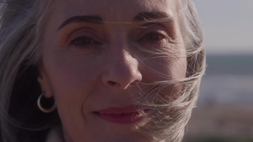 The wind blows the womans hair on her face