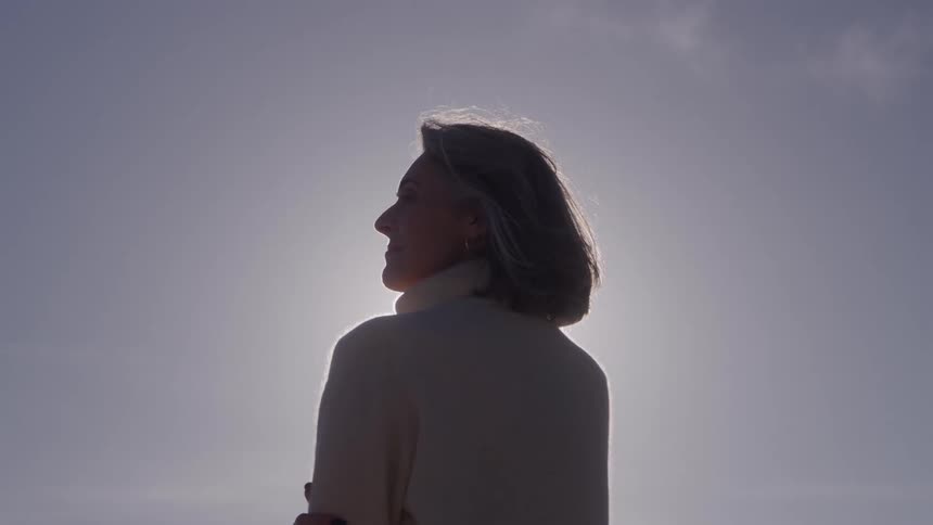 Wind blows the womans hair that has her arms folded
