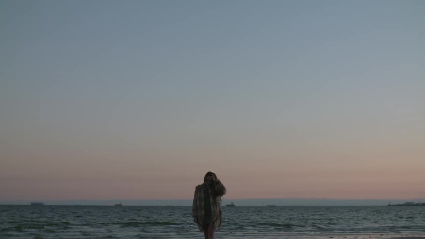 Woman walking by the water at sunset
