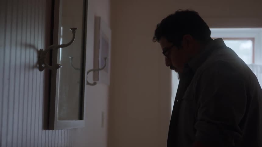 The video is a dimly lit closeup shot of a persons hands over a bathroom sink framed from the waist up the person is wearing a dark collared shirt and is leaning over the white porcelain sink basin