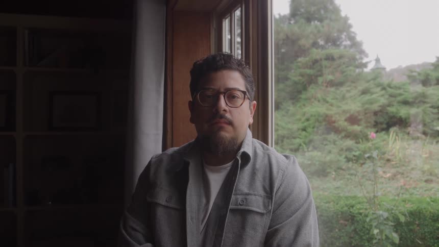 Man with glasses near a window overlooking the garden