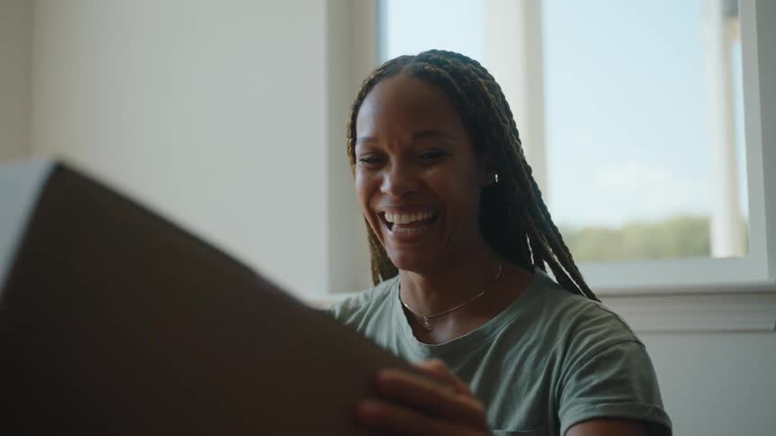 Someone hands a smiling woman an empty cardboard box