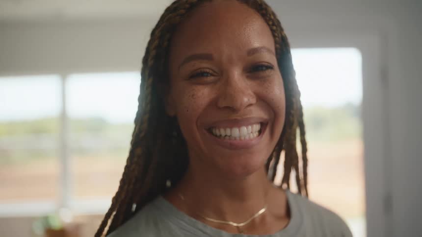 A woman with long braids smiles toward the camera